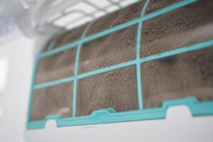 Closeup of dirty dust air conditioner filter on wall. Home air conditioner maintenance